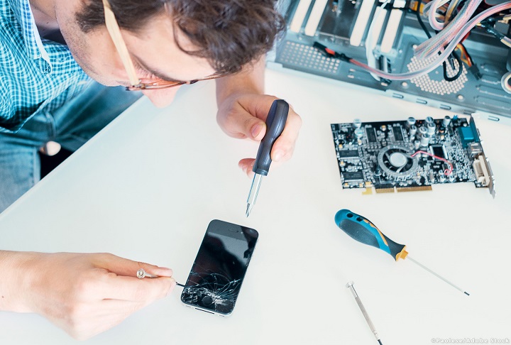 Repairman changing broken smartphone screen in service center
